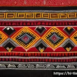 Home 21 동티모르 공예품 구매 가이드 - A vibrant Dongtimor traditional textile displayed on a wooden table, featuring intricate handwoven c...